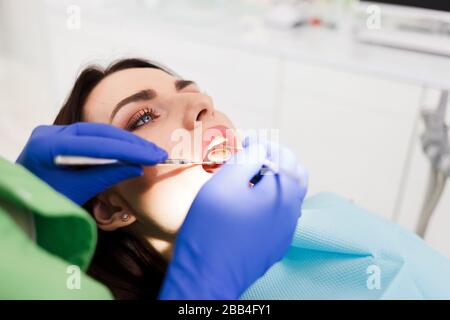 Il medico esamina la cavità orale del paziente. La donna tratta i denti da vicino alla clinica dentale Foto Stock