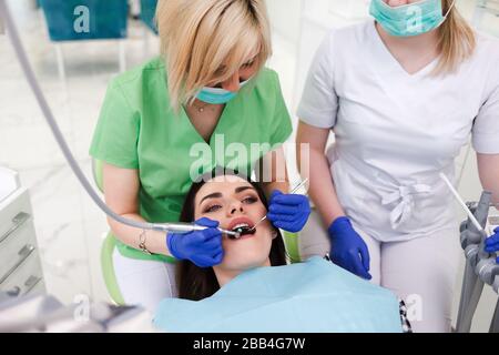 Dentista e assistente trattano i denti di un paziente Foto Stock