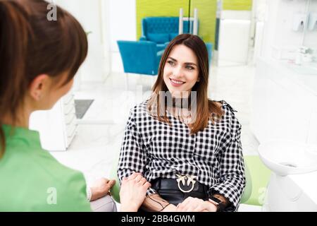 Il dentista e il paziente parlano di trattamento. Il medico dentale femminile ha messo la sua mano sulla donna Foto Stock