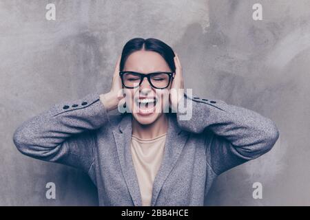 Primo piano di una donna brunetta stressata che urla con occhi e orecchie chiusi Foto Stock