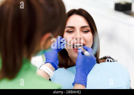 Dentista medico fora i denti con un trapano a una giovane donna. Ragazza a appuntamento del dentista Foto Stock