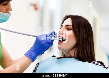 Dentista medico fora i denti con un trapano a una giovane donna. Ragazza a appuntamento del dentista Foto Stock