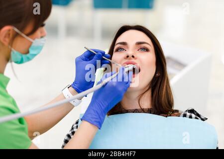 Dentista medico fora i denti con un trapano a una giovane donna. Ragazza a appuntamento del dentista Foto Stock