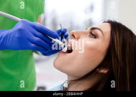 La donna tratta i denti presso la clinica dentale. Il medico dentista utilizza la perforazione per perforare i denti del paziente Foto Stock