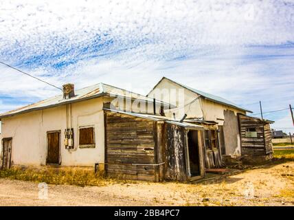 Vecchia casa di stucco con le finestre a bordo e Shed weathered Foto Stock
