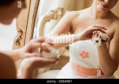 Closeup di donna piuttosto giovane che tiene il vaso di lozione idratante in mano. Riflessione in specchio di tenera bella ragazza che applica la crema sul suo corpo. Be Foto Stock