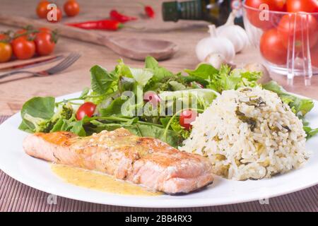 Filetto di salmone, salsa di frutti di passione, riso e insalata fresca e sana su un tavolo di legno Foto Stock