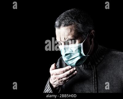 uomo con maschera chirurgica starnutisce o tossisce. Pandemia o epidemia e concetto di paura, paura o pericolo. Protezione per rischio biologico come COVID-19 aka Corona Foto Stock