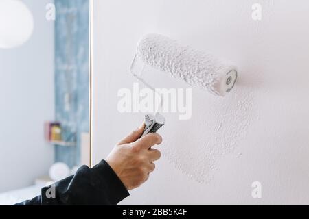 dipinto a mano un muro in bianco con un rullo, decorazione domestica e concetto di ristrutturazione, foto orizzontale Foto Stock