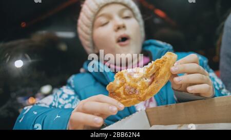 Bambino mangiare pizza formaggio quattro. Primo piano di ragazza giovane donna mangiare pizza e masticare in ristorante all'aperto. Bambini mani prendere pezzo pizza. Foto Stock