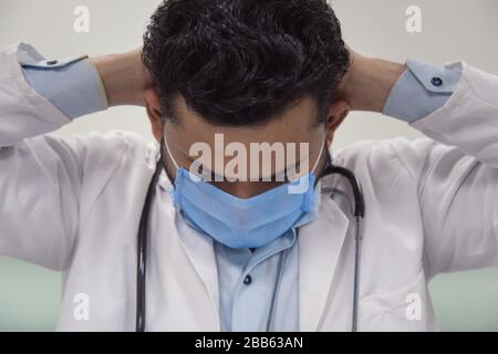 Il dottore disperato tiene la testa in su con la mano. Concetto di stress e fallimento sul lavoro. Isolato su bianco. Foto Stock