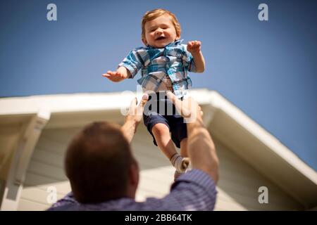 Ragazzo felice che viene catturato da suo padre. Foto Stock