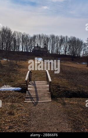 Un ponte con ringhiera in legno nella tenuta della famiglia Pushkin. Lo stagno è coperto di ghiaccio e neve. Il ponte ha una forma arcuata. Russia Foto Stock