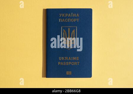 Passaporto straniero dell'Ucraina, isolato sul giallo brillante sfondo soleggiato. Concetto di viaggio alla moda, viaggi ucraini Foto Stock