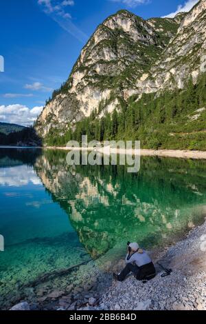 Donna seduta sul Lago di Braies scatta una foto, Alto Adige, Italia Foto Stock