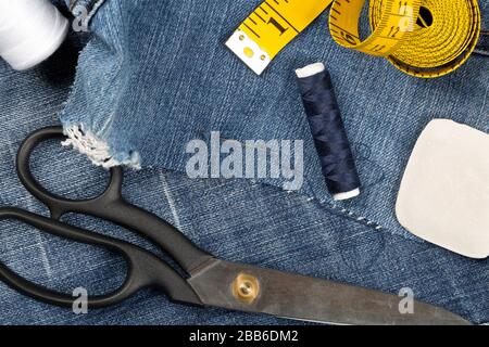 Pantaloni in tessuto di cotone denim blu strappato con utensili su misura - jeans moda concetto di riparazione o di riparazione, piatto vista dall'alto Foto Stock