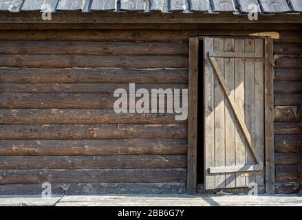 Sfondo in legno con una porta. Vecchio muro di legno di una casa rustica con struttura e porta. Foto Stock