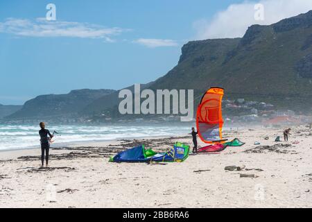Kitesurfers che si preparano prendere alle onde sulla spiaggia su Baden Powell Drive, False Bay, Città del Capo, Sudafrica Foto Stock
