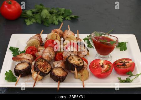 Shish kebab dalla turchia con verdure: Zucchine, melanzane, cipolla, pomodoro e pepe situato su un piatto bianco con salsa e pomodori Foto Stock