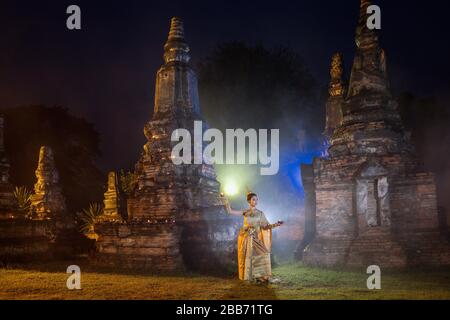 Donna in costume tradizionale di fronte a un tempio, Bangkok, Thailandia Foto Stock