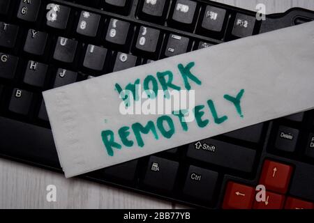 Lavorate in remoto scrivendo su una carta tissue e su un computer con tastiera isolato su Office Desk. Foto Stock