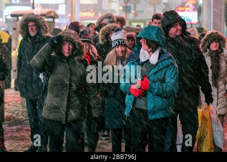 Le persone che si trovano a una luce rossa durante la nevicata pesante in Time Square, Manhattan, New York City, Stati Uniti d'America Foto Stock