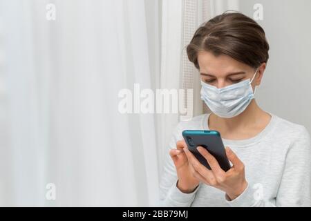Una donna in una maschera medica sta parlando al telefono. Foto Stock