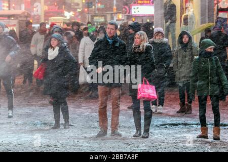 Persone in piedi a luce rossa durante la neve Blizzard a Times Square, New York City, USA Foto Stock