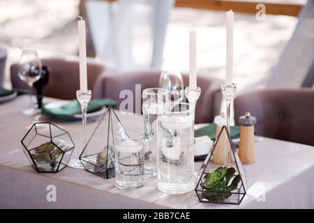 Festive tavolo da nozze con fiori, tovaglioli, posate, bicchieri e candele, luminoso arredamento da tavolo estivo. Decorazioni per matrimoni Foto Stock