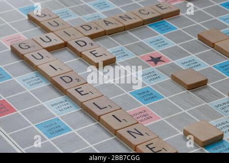 Indicazioni, linee guida e parole guida scritte su una scrabble board associata alla pandemia del Coronavirus Covid-19 Foto Stock