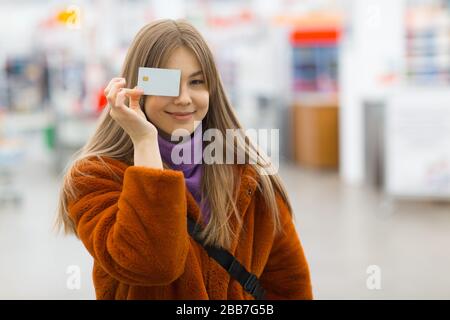 La giovane donna tiene la carta di credito nelle mani vicino al viso Foto Stock