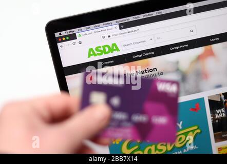 Il sito web ASDA è raffigurato su un laptop con una carta bancaria in quanto i siti web di Supermarket sono sopraffatti da ordini online durante la pandemia di Coronavirus COVID-19 mentre il Regno Unito continua a bloccarsi per contribuire a frenare la diffusione del coronavirus. Foto Stock