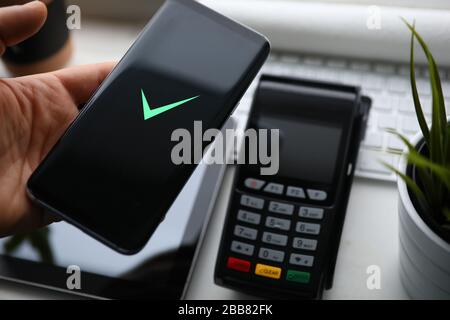 Mani ravvicinate che tengono lo smartphone vicino al terminale Foto Stock