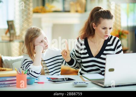 annoiati bambini che desiderano l'attenzione mentre la madre occupata che lavora in ufficio domestico nella casa moderna nel giorno di sole. Foto Stock