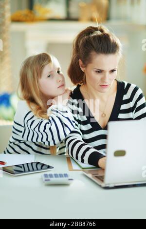 annoiati bambini che desiderano l'attenzione mentre la madre occupata che lavora in ufficio domestico nella casa moderna nel giorno di sole. Foto Stock