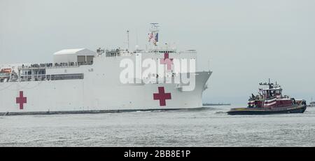 New York, NY - 30 Marzo 2020: Nave USNS Comfort Navy con 1000 posti letto per soccorere gli ospedali di New York su passaggi pandemici COVID-19 sotto il ponte Verrazzano-Narrows sulla sua strada nel porto di New York Foto Stock