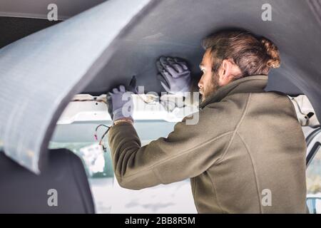 Uomo che lavora sull'isolamento all'interno del suo camper van Foto Stock