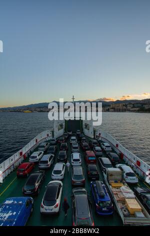 Vista dello Stretto di Messina e del porto di Messina, dal traghetto che la attraversa, con auto e camion all'interno del traghetto stesso Foto Stock