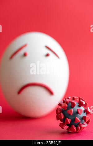 Modello di coronavirus plastificato e isolato di uovo su sfondo rosso. Modello plastilina di coronavirus e uovo di pasqua raffigurante paura e tristezza. Grande Foto Stock