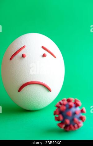 Modello di coronavirus plastificato e isolato di uovo su sfondo verde. Modello plastilina di coronavirus e uovo di pasqua raffigurante paura e tristezza Foto Stock