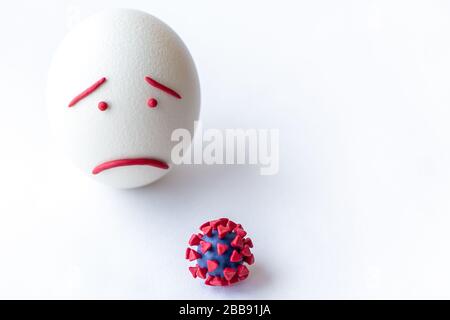 Modello di coronavirus plastificato e isolato di uovo su sfondo bianco. Modello plastilina di coronavirus e uovo di pasqua raffigurante paura e tristezza Foto Stock