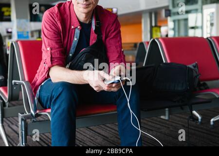 Viaggiatore con dispositivi elettronici presso il terminal dell'aeroporto Foto Stock