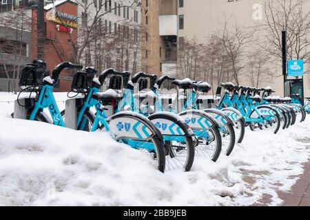 Una fila di moto divvy coperte di neve durante una tempesta di neve Foto Stock