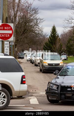 Detroit, Michigan, Stati Uniti. 30th Mar, 2020. La gente ha aspettato nelle loro automobili ad un luogo di distribuzione della banca alimentare di Gleaners in un quartiere pesantemente ispanico. La necessità di cibo è aumentata drammaticamente a Detroit nella scorsa settimana. In questo sito, il cibo si esaurì mentre molti erano ancora in attesa, e un poliziotto ha guidato giù la linea di automobili passando il messaggio sul suo altoparlante: 'No mas comida' (No more food). Credito: Jim West/Alamy Live News Foto Stock