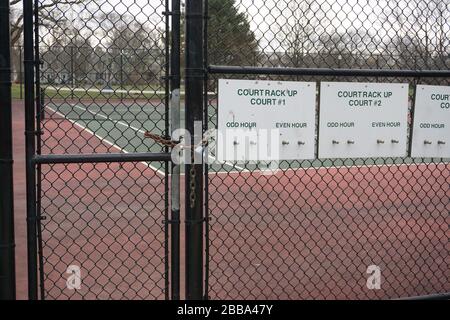 I campi da tennis in un parco suburbano sono chiusi a lucchetto per applicare le misure di distanza sociale durante la pandemia di Coronavirus. Foto Stock