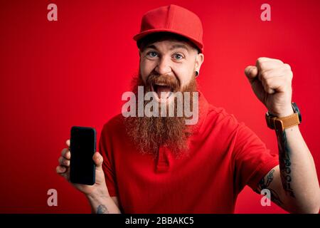 Redhead irlandese consegna uomo con barba che tiene smartphone mostra app sullo schermo urlando orgoglioso e celebrare la vittoria e il successo molto eccitato, coraggio Foto Stock
