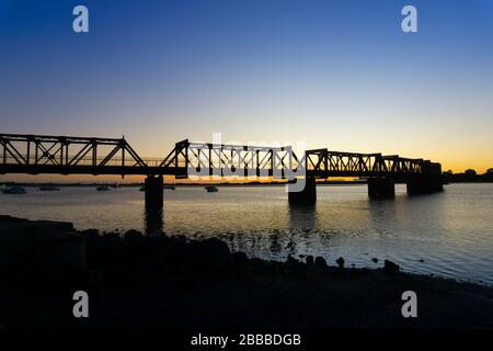 Il Ponte storico della Ferrovia di Tauranga si staglia alla luce del mattino presto contro l'alba. Foto Stock