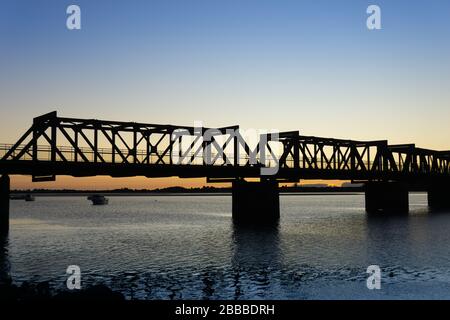Il Ponte storico della Ferrovia di Tauranga si staglia alla luce del mattino presto contro l'alba. Foto Stock