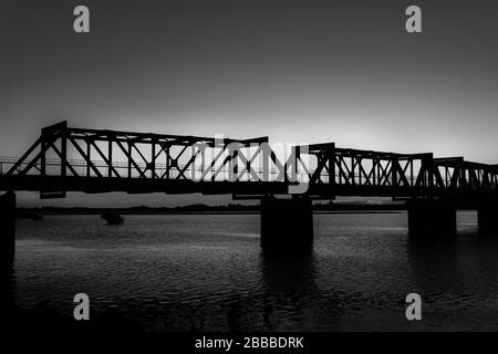 Il Ponte storico della Ferrovia di Tauranga si staglia alla luce della mattina presto contro l'alba in bianco e nero. Foto Stock