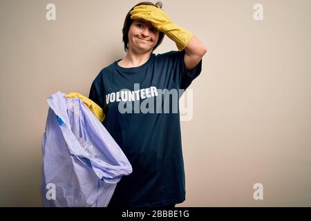 Sindrome di Young Down volontario donna che raccoglie rifiuti e plastica dai rifiuti stressati con la mano sulla testa, scioccato con vergogna e sorpresa viso, arrabbiato Foto Stock